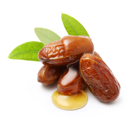 Four jojoba pods dripping in jojoba oil with green leaves on a white background