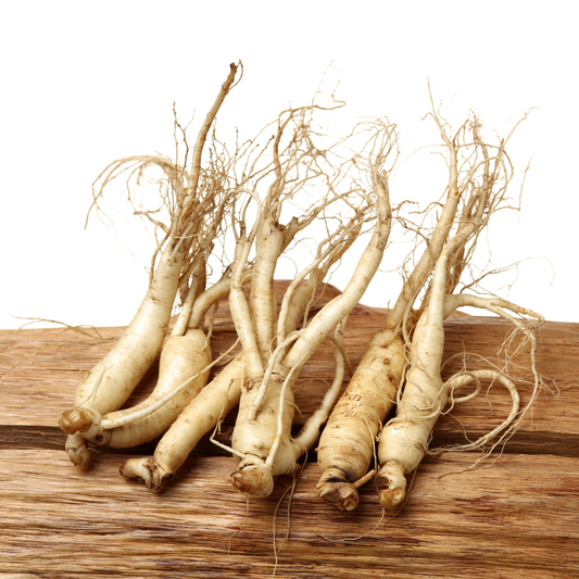Six ginseng roots with thread-like roots displayed on a wooden plank against a white background
