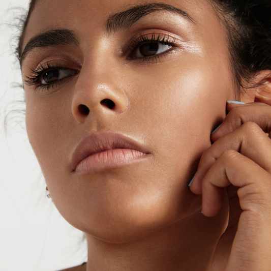 Headshot of a young brown-skinned woman with smooth, even-toned skin looking away from the camera