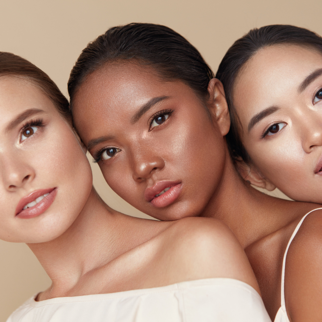 caucasian, african aThree young women of diverse skin tones — Caucasian, African American, and Asian — leaning together showing the importance of sun protection for all skin tones.merican and asian girl group headshot.